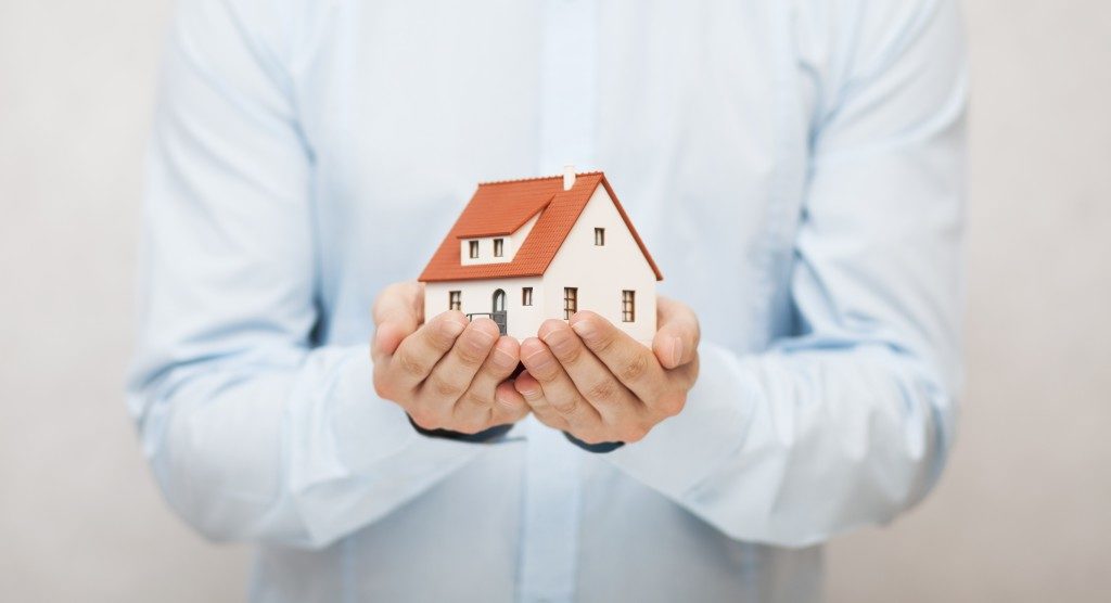 person holding a house miniature with both hands