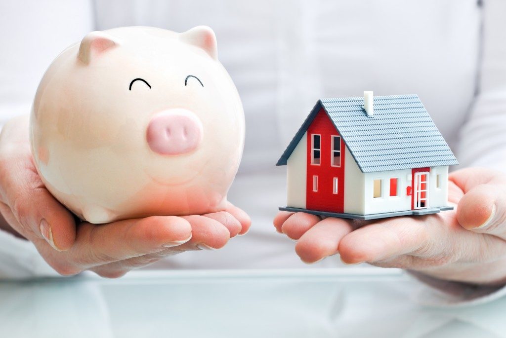 hands holding piggy bank and house model