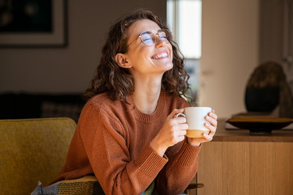 woman relaxing at home while holding a cup of coffee